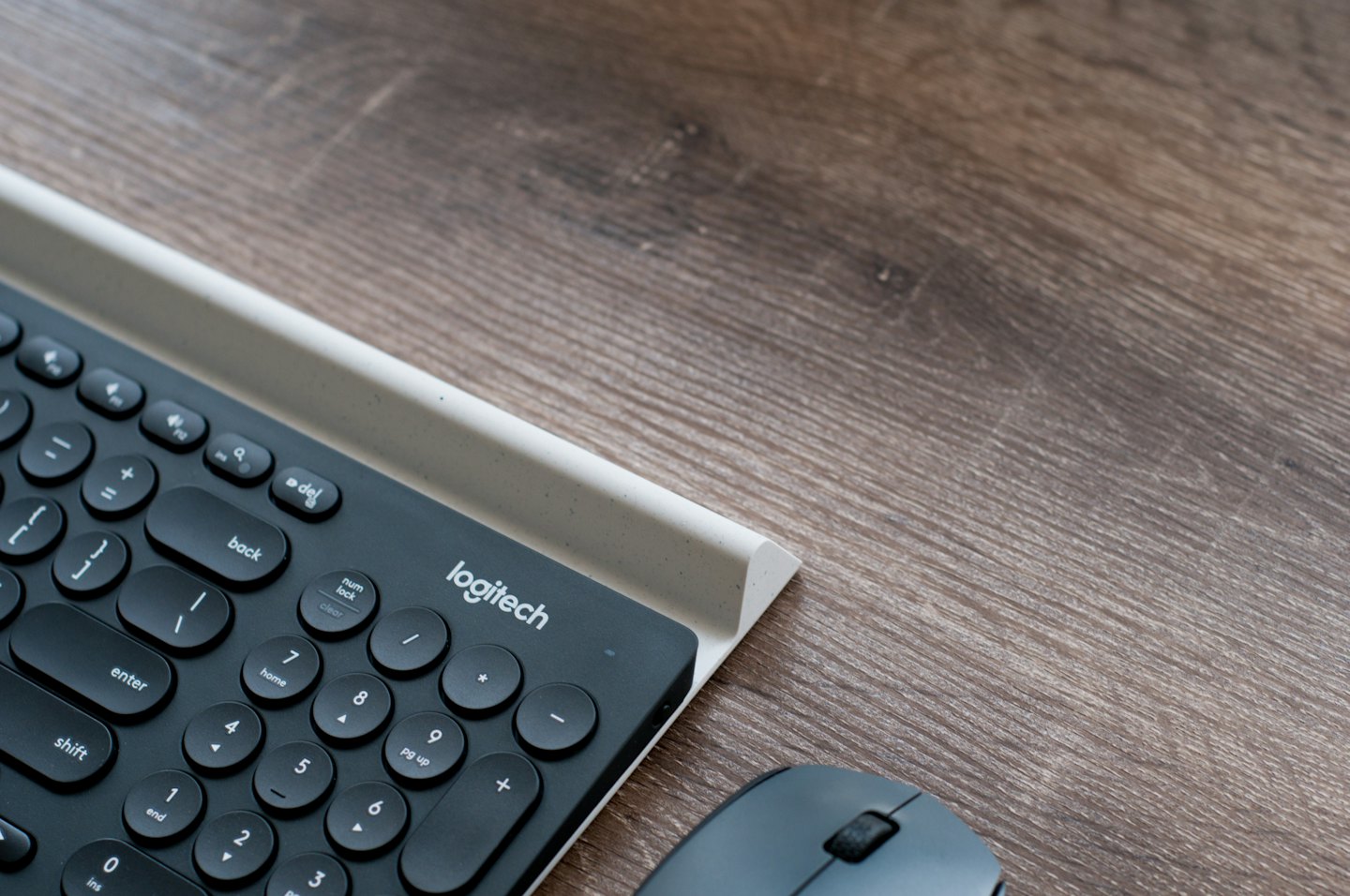 A modern wireless keyboard and mouse on a wooden desk.